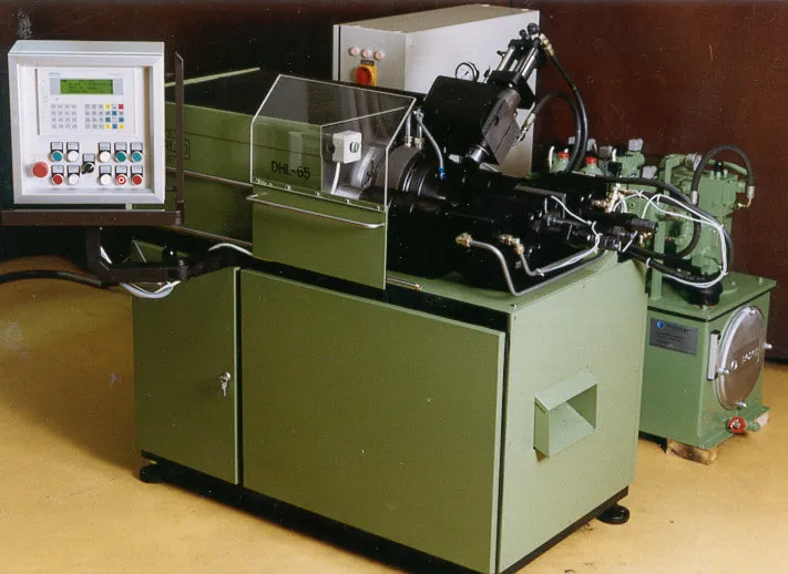 Archive photo of Harlo's early machine, the DHL-65: green machine body, operator panel standing on the left, hydraulic power unit on the right